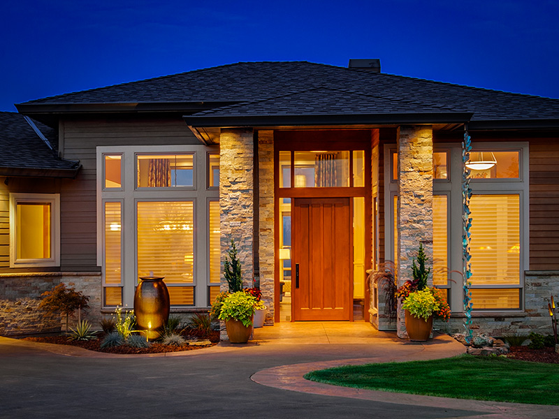 Residential front entry with illuminated windows and stone detailing at blue hour